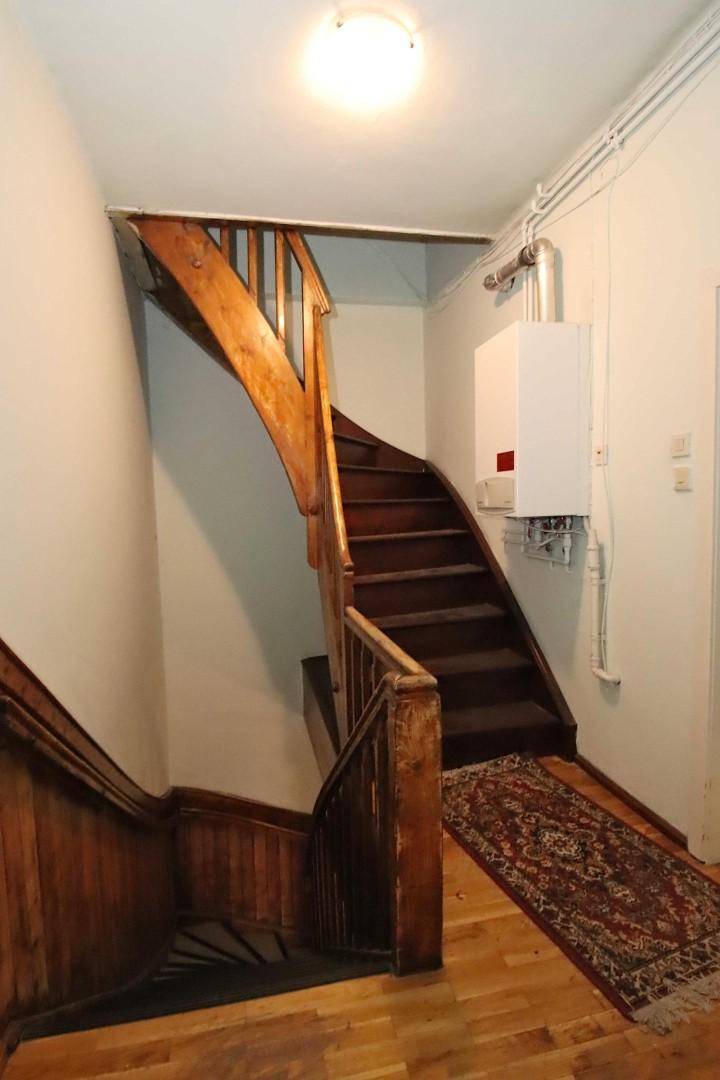 Holztreppe in einem traditionellen Treppenhaus mit Gastherme an der Wand.