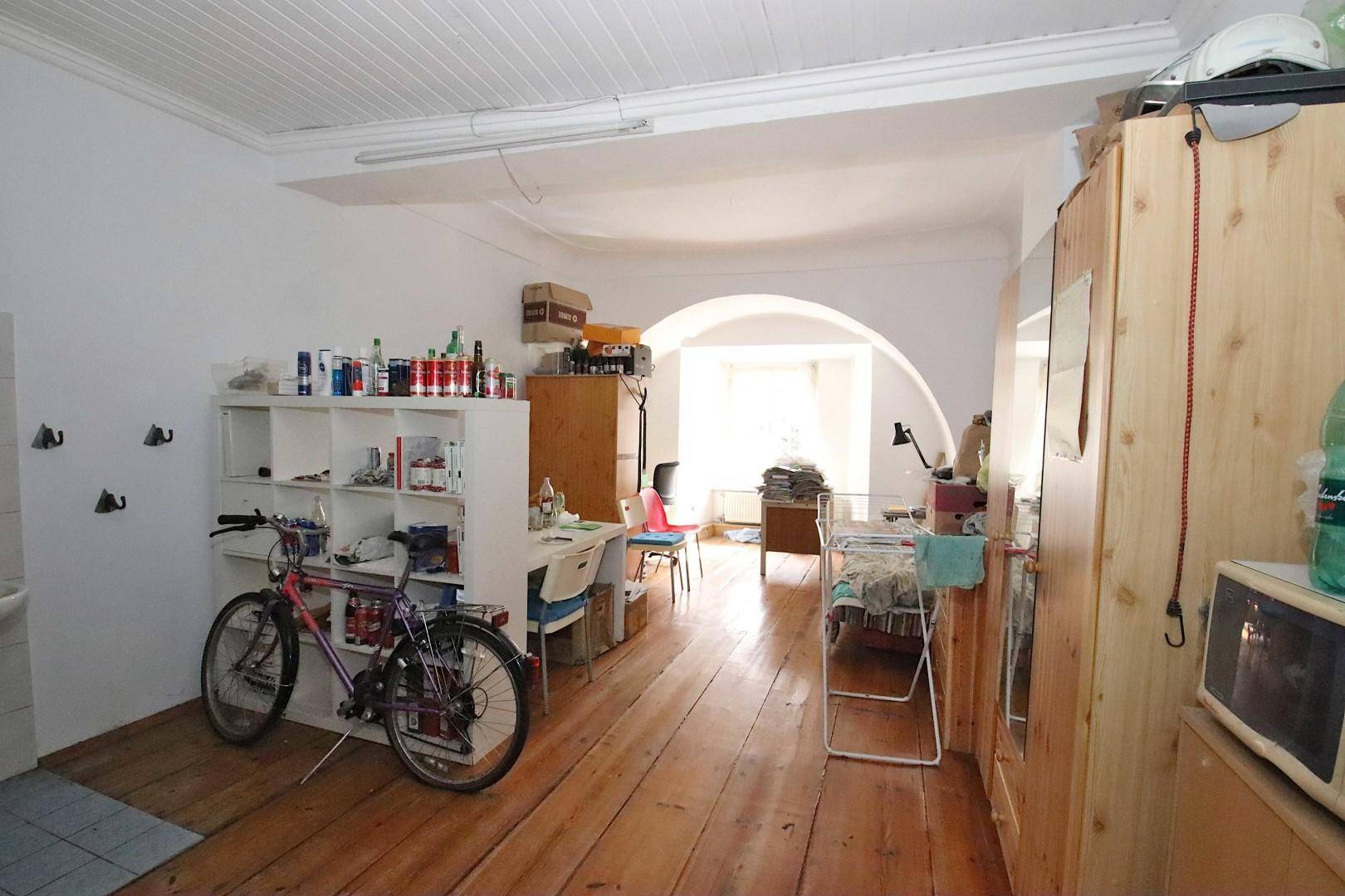 Großer Raum mit Holzdielenboden, Regalen und einem Fahrrad.