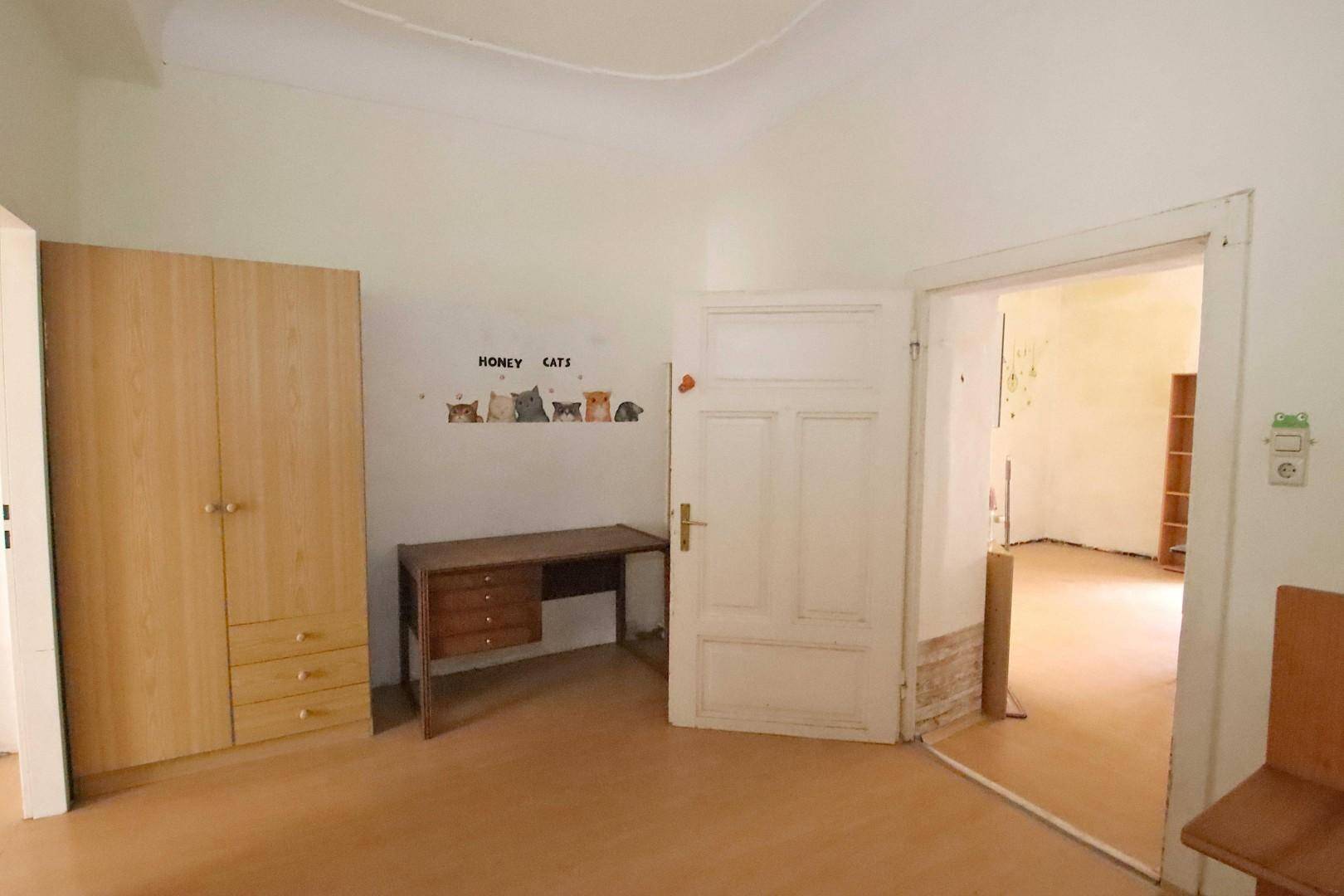 Schlafzimmer mit Holzschrank, Schreibtisch und Parkettboden.