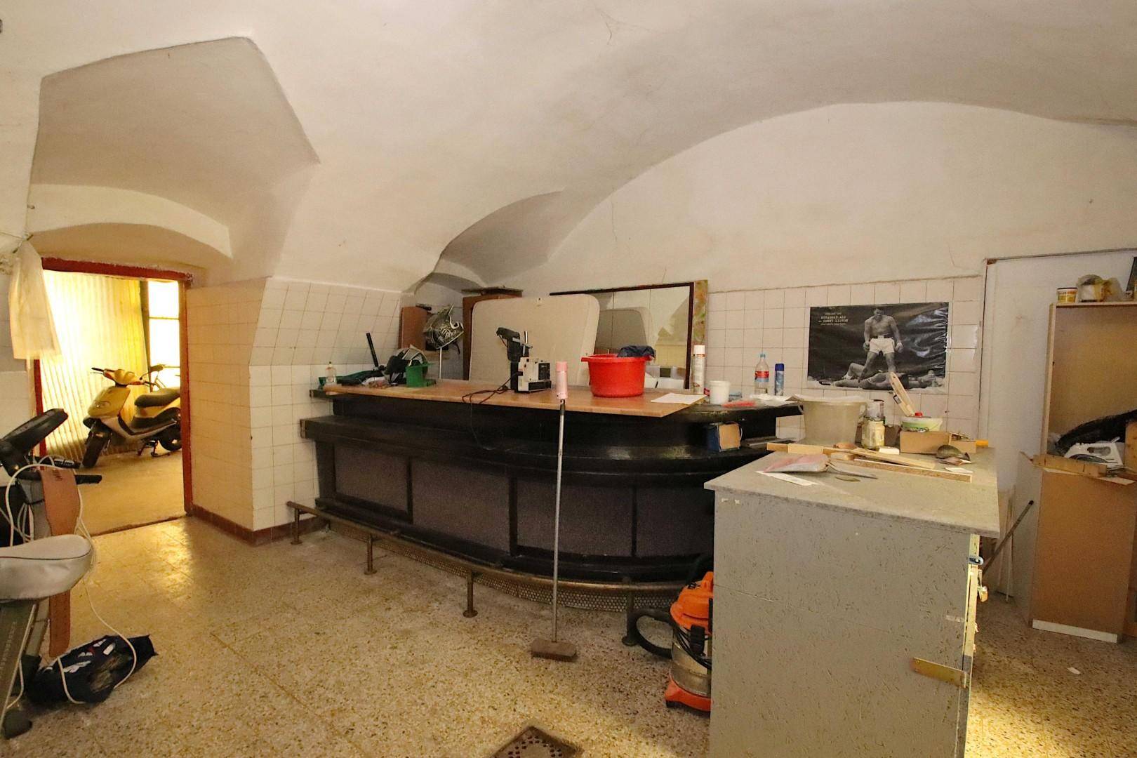 Kellerraum mit einer Bar, Fliesenboden und gewölbter Decke.