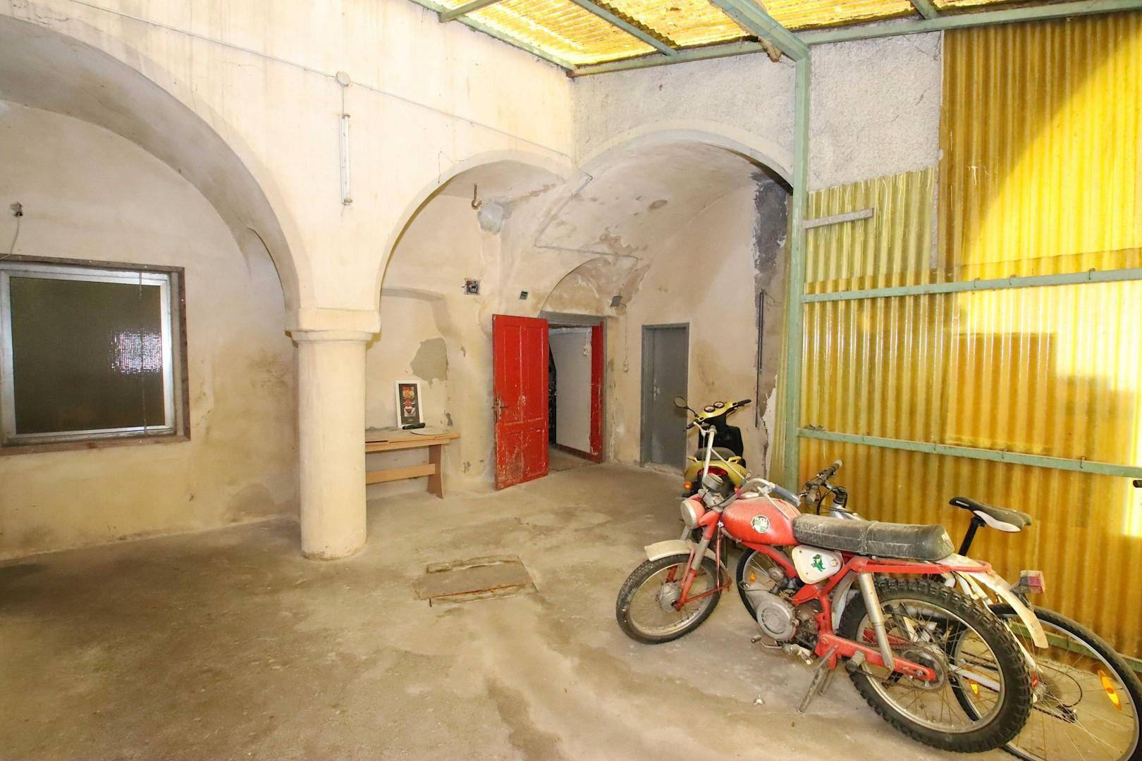 Geräumige Garage oder Lagerhalle mit Motorrädern und gewölbter Decke.