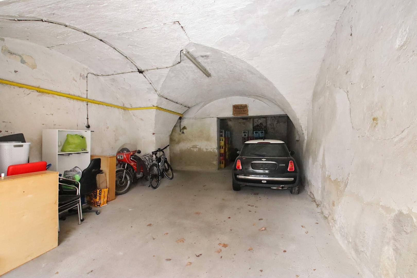 Tiefgarage mit einem Auto, Motorrädern und gewölbter Decke.