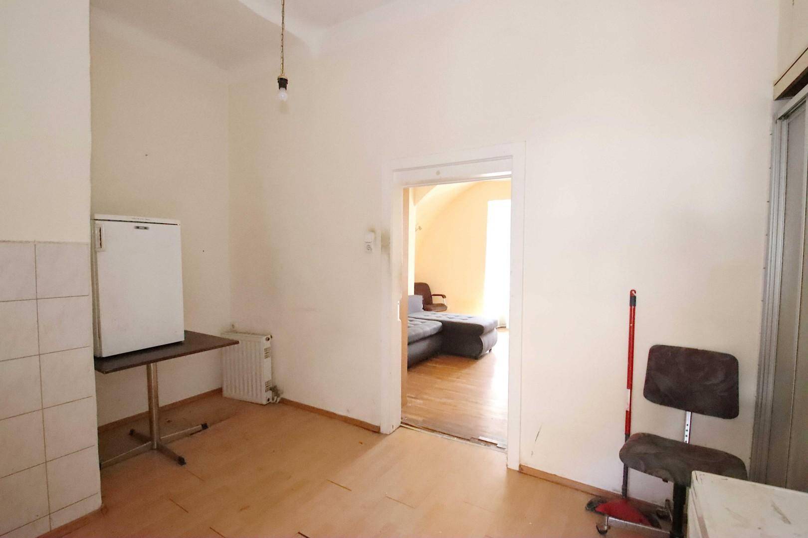 Raum mit Kühlschrank und Tisch, der zu einem weiteren Zimmer führt.