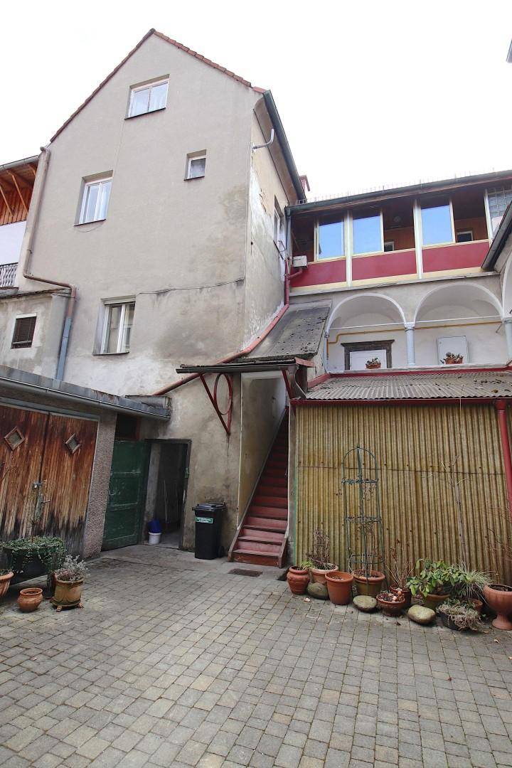 Gepflasterter Innenhof mit Topfpflanzen und Zugang zu Garagen und einem Nebengebäude.