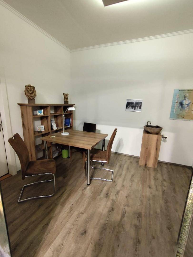 Kleines Büro mit Holzlaminatboden, einem Schreibtisch, Stühlen und einem rustikalen Waschbecken aus Holz.