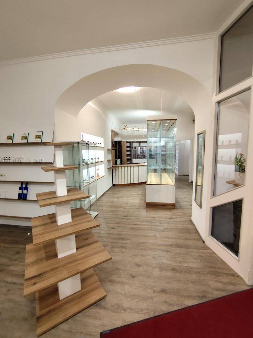 Eingangsbereich eines Gewerbeobjekts mit Holzlaminatboden, modernen Regalen und einer offenen Gestaltung.