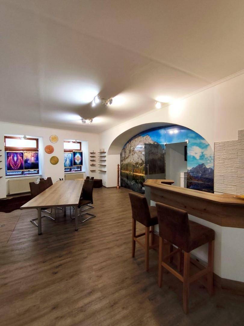 Heller Gewerberaum mit Holzlaminatboden, einer modernen Theke und einer großen Berglandschaft als Wandbild.
