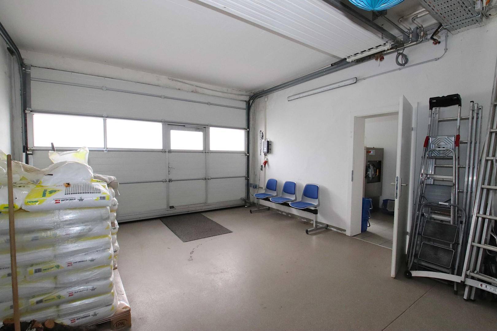 Große Garage mit Rolltor, Fenstern und Sitzgelegenheiten, ideal für Lagerung oder Fahrzeuge.