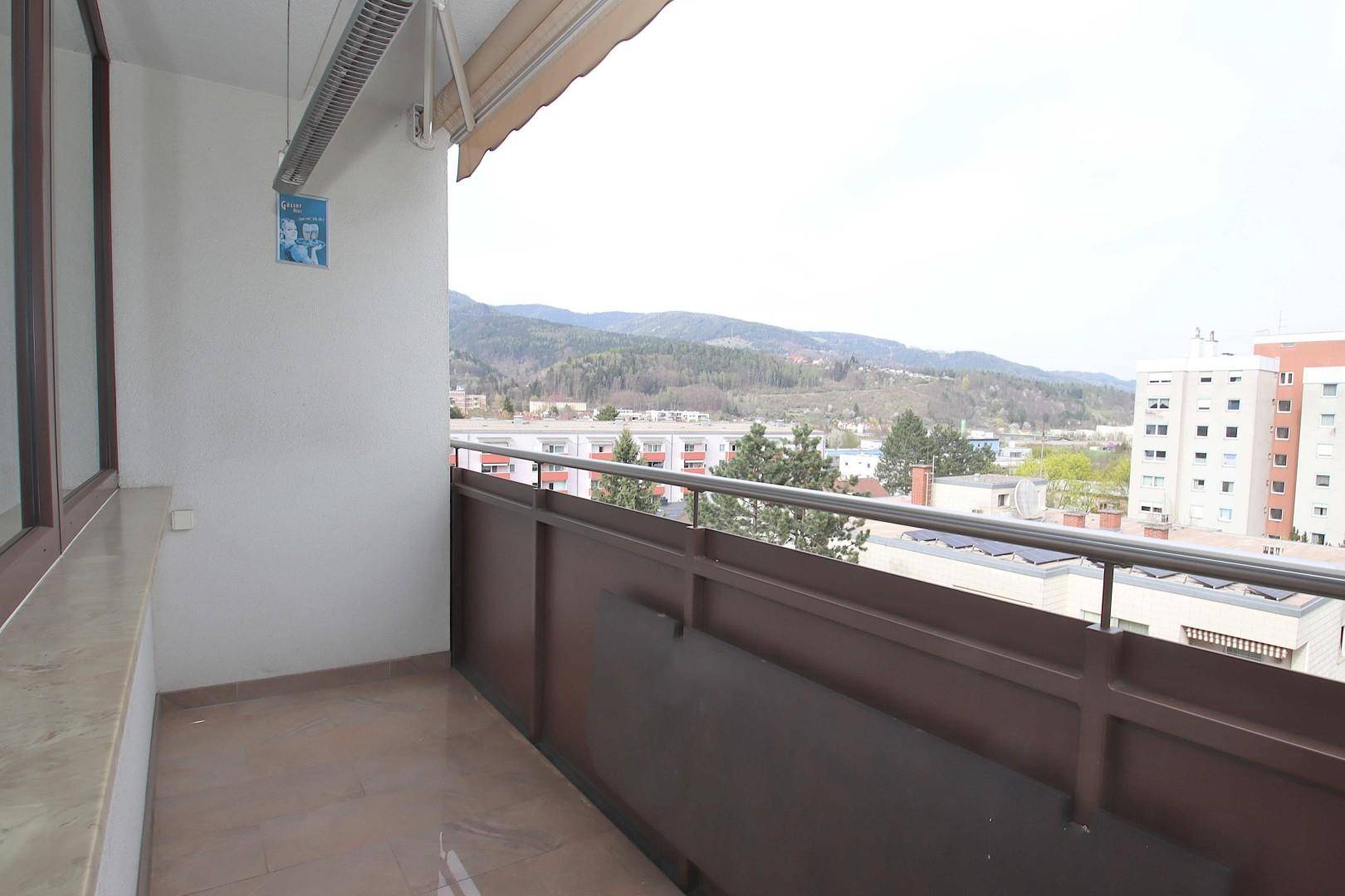 Balkon mit Fliesenboden und weitem Blick über die Stadt und die umliegenden Berge.