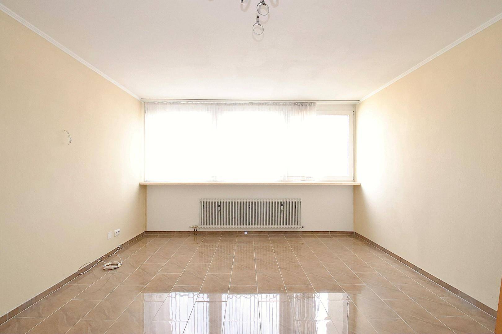 Geräumiges Zimmer mit Fliesenboden und großem Fenster, bietet vielseitige Nutzungsmöglichkeiten.