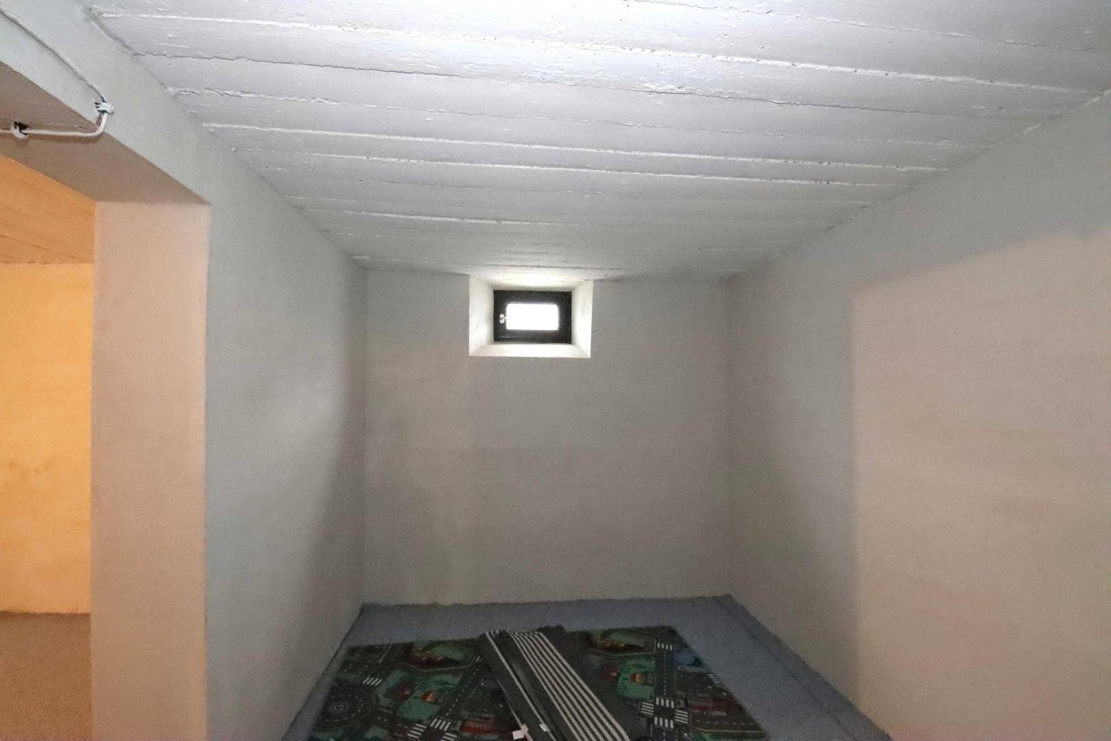 Kellerraum mit kleinem Fenster und einfacher Ausstattung, ideal als Abstellraum.