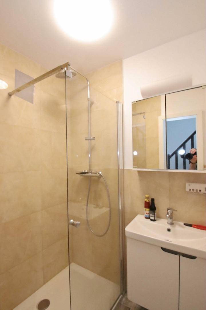 Modernes Badezimmer mit Duschkabine, Waschbecken und Spiegelschrank.