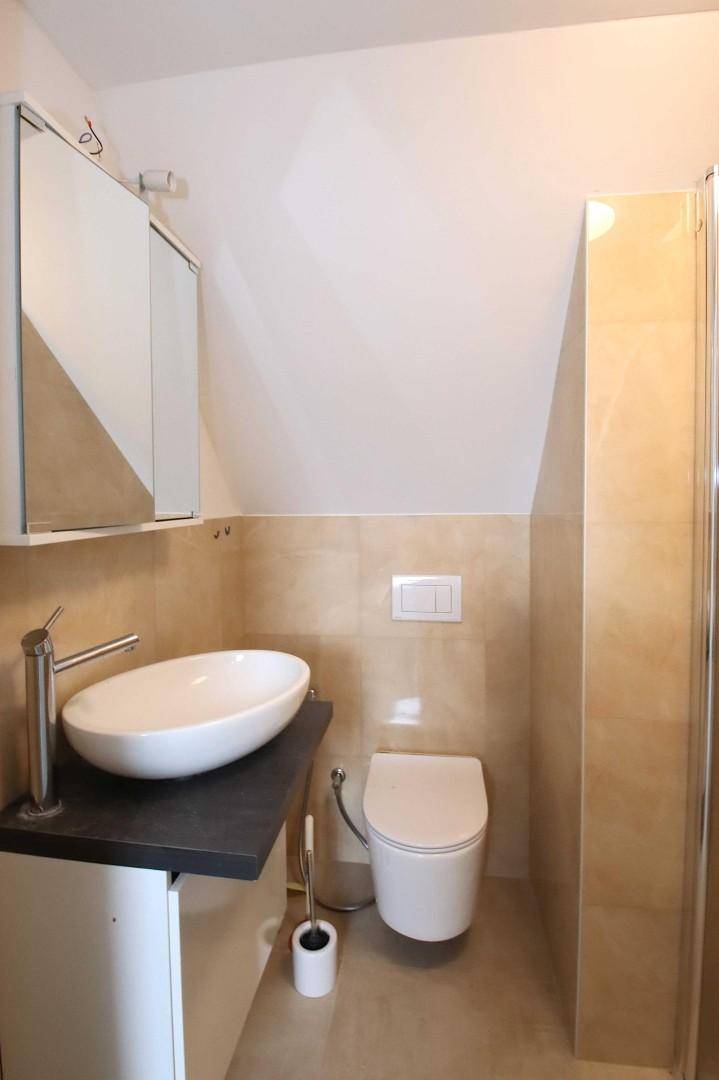 Helles Badezimmer im Dachgeschoss mit modernem Aufsatzwaschbecken und WC.