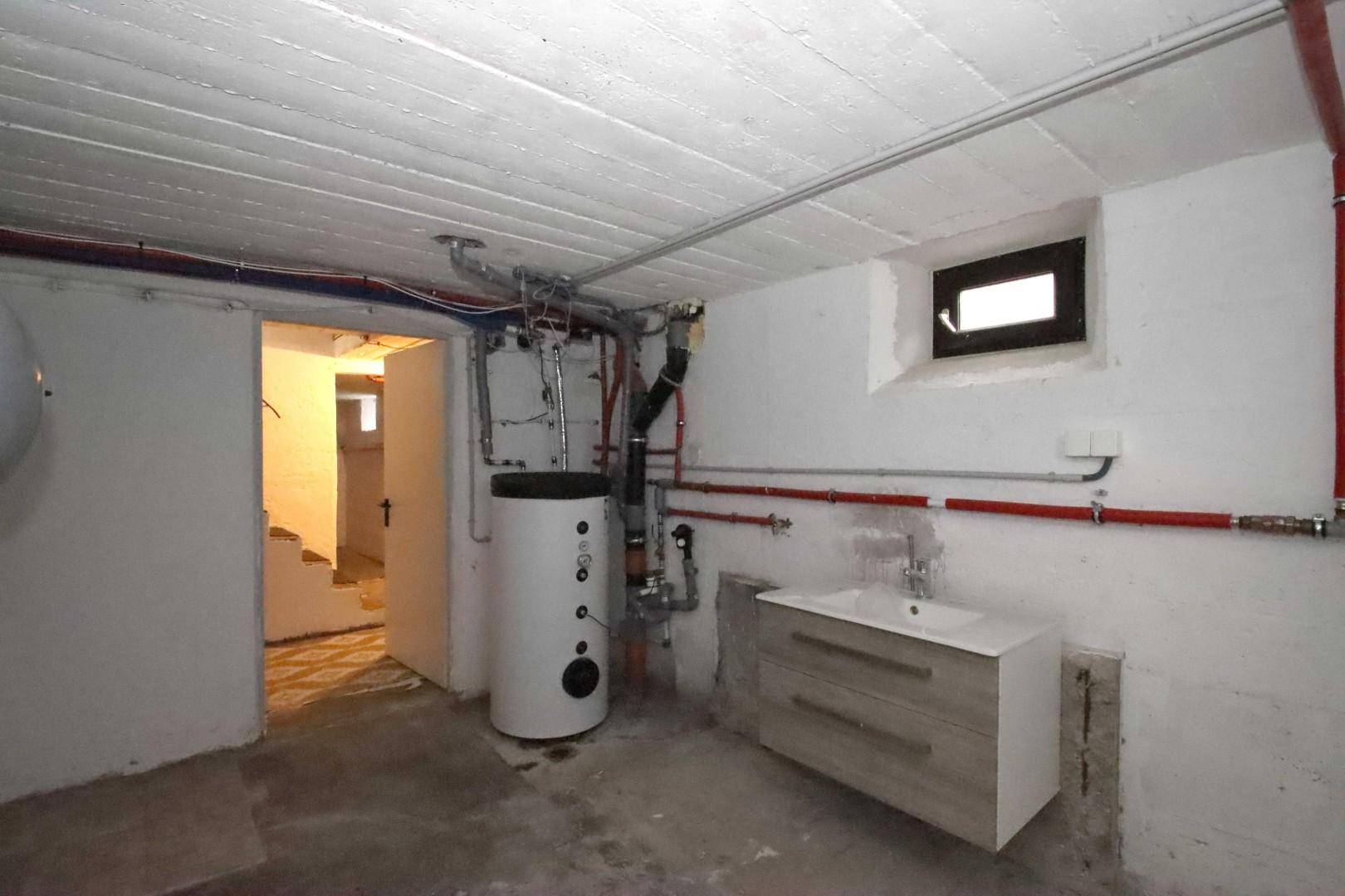 Hauswirtschaftsraum im Keller mit Warmwasserspeicher und Waschbecken.