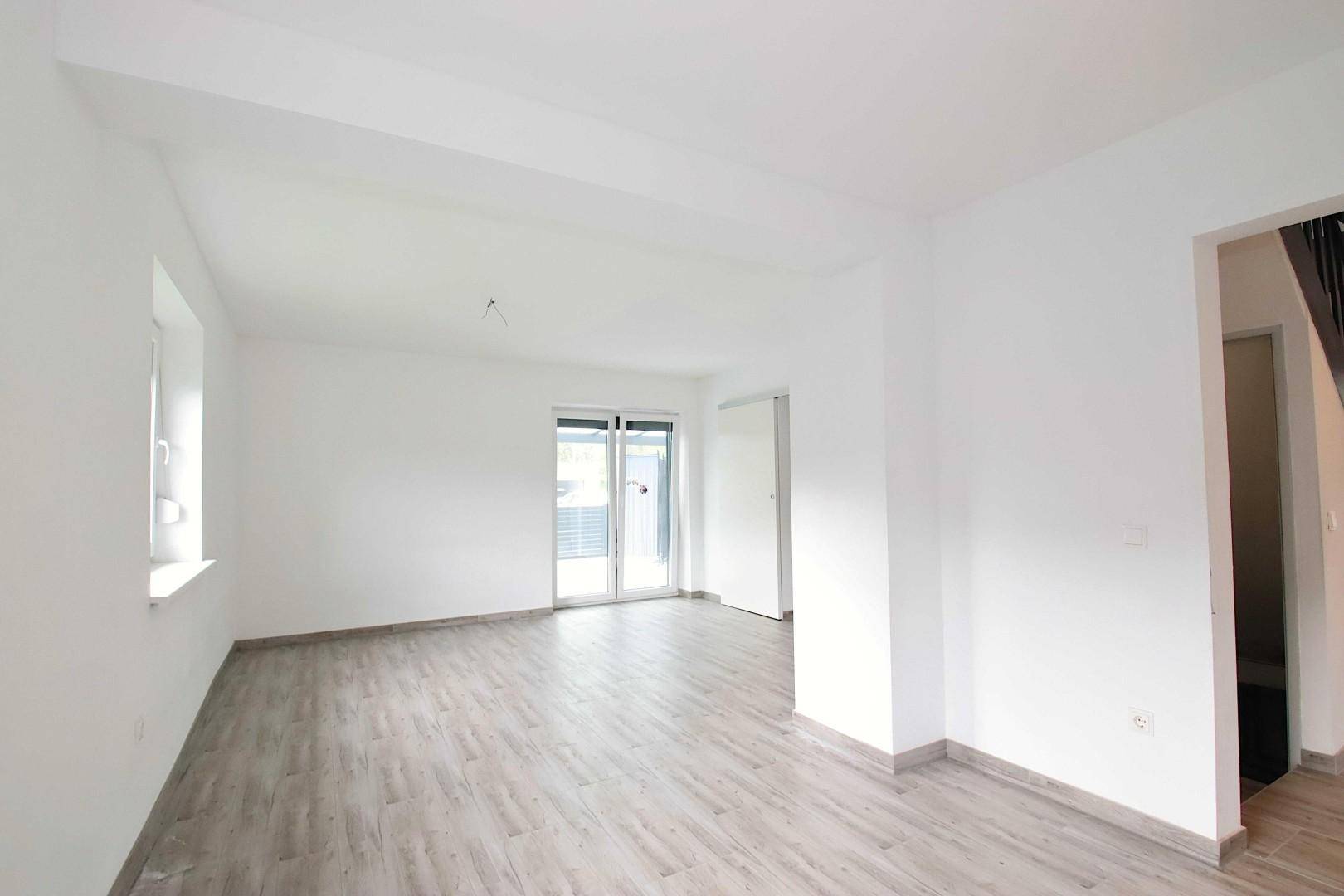 Geräumiges, helles Wohnzimmer mit Laminatboden und Zugang zur Terrasse.