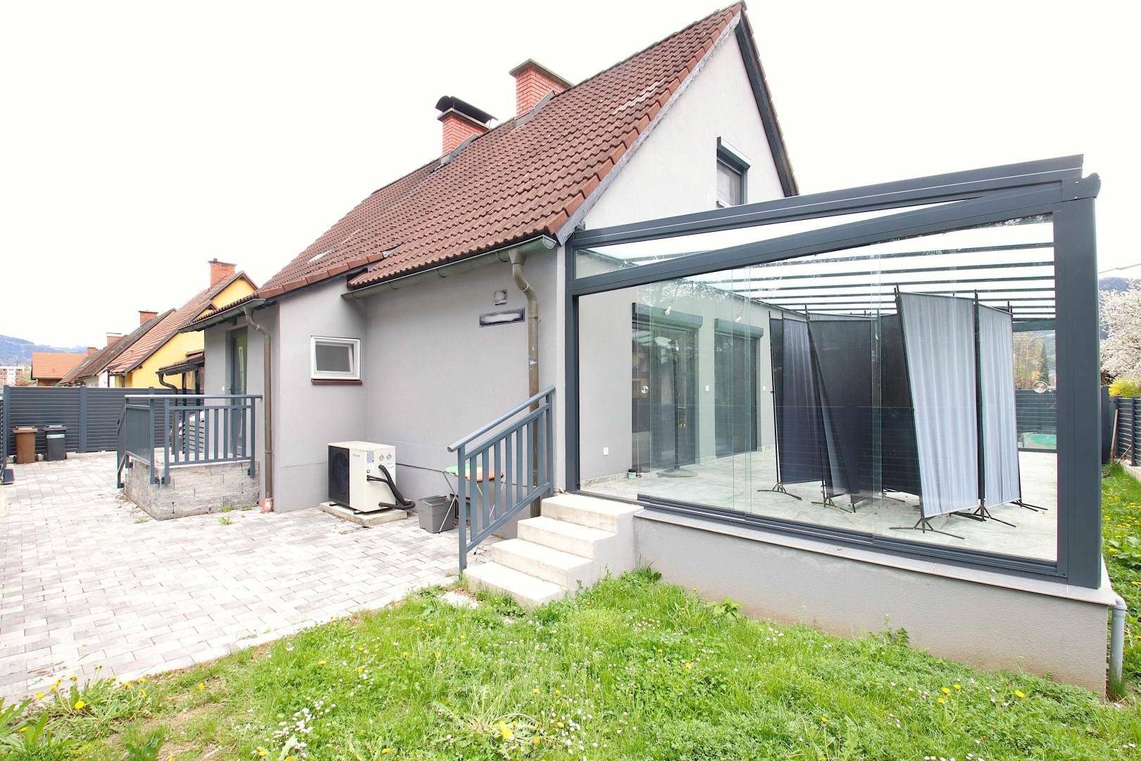 Rückansicht des Hauses mit Wintergarten und gepflastertem Bereich, der zum Verweilen einlädt.