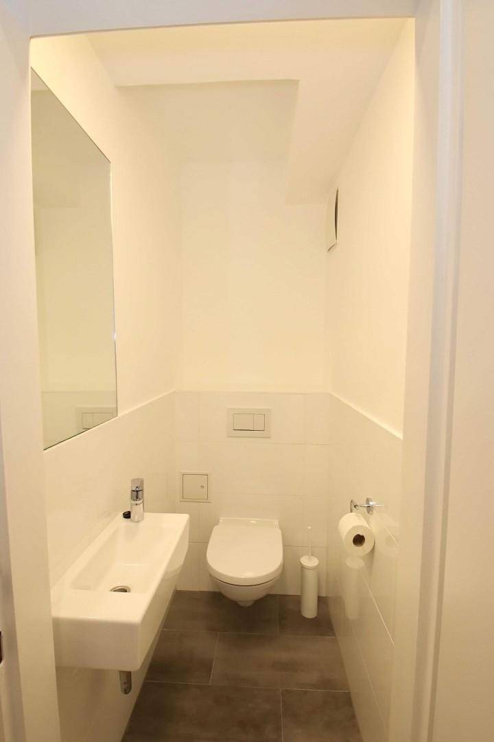 Kompaktes Gäste-WC mit modernem Design, wandhängender Toilette und praktischem Waschbecken.