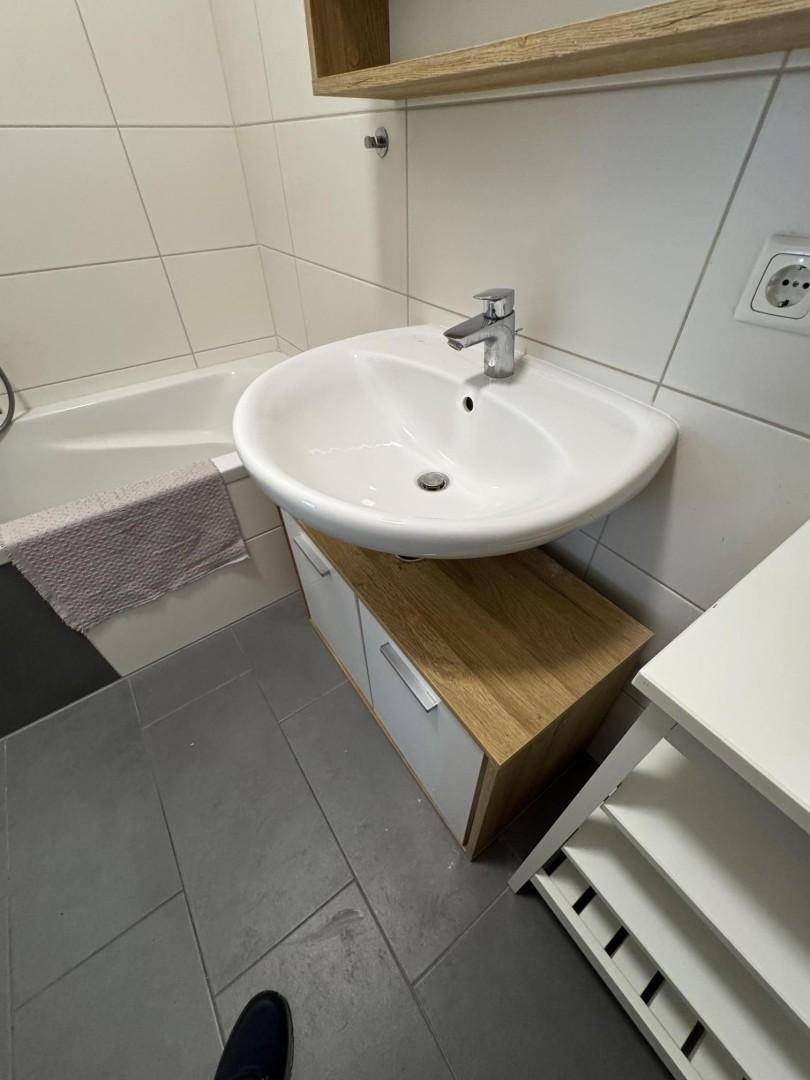 Modernes Badezimmer mit Waschbecken, Badewanne und grauen Fliesen.