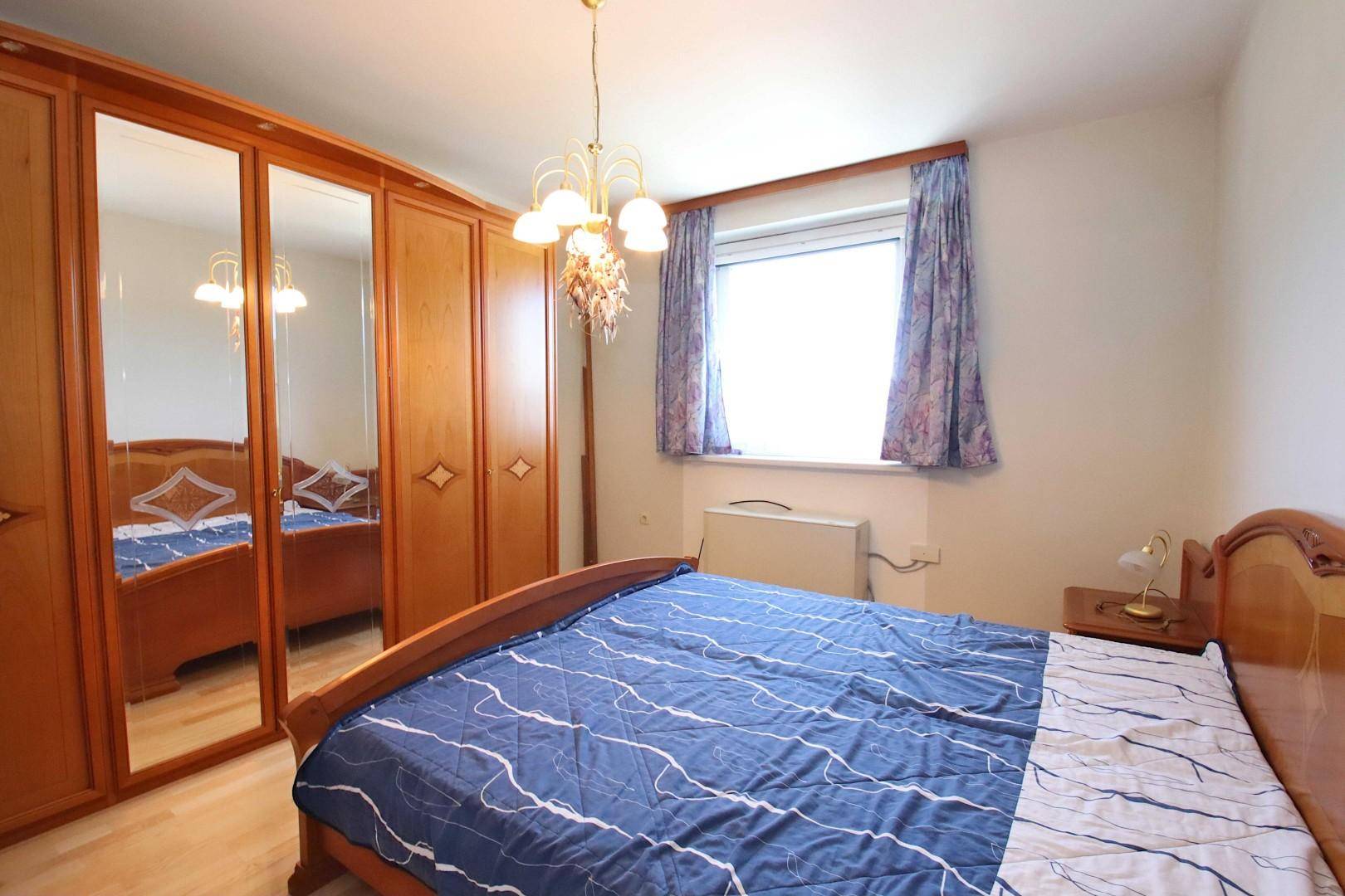 Schlafzimmer mit großem Doppelbett, Spiegelschränken und einem Fenster.