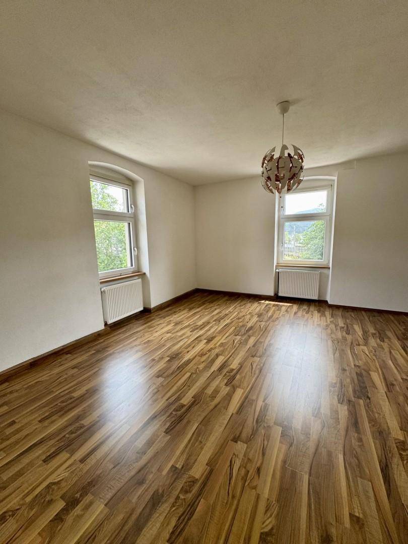 Heller, leerer Raum mit Laminatboden und zwei Fenstern, ideal für Wohn- oder Schlafzimmer.
