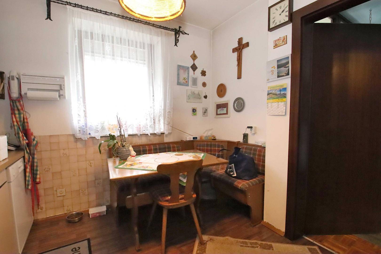 Essbereich in der Küche mit einer gemütlichen Eckbank, Fenster und traditioneller Dekoration.