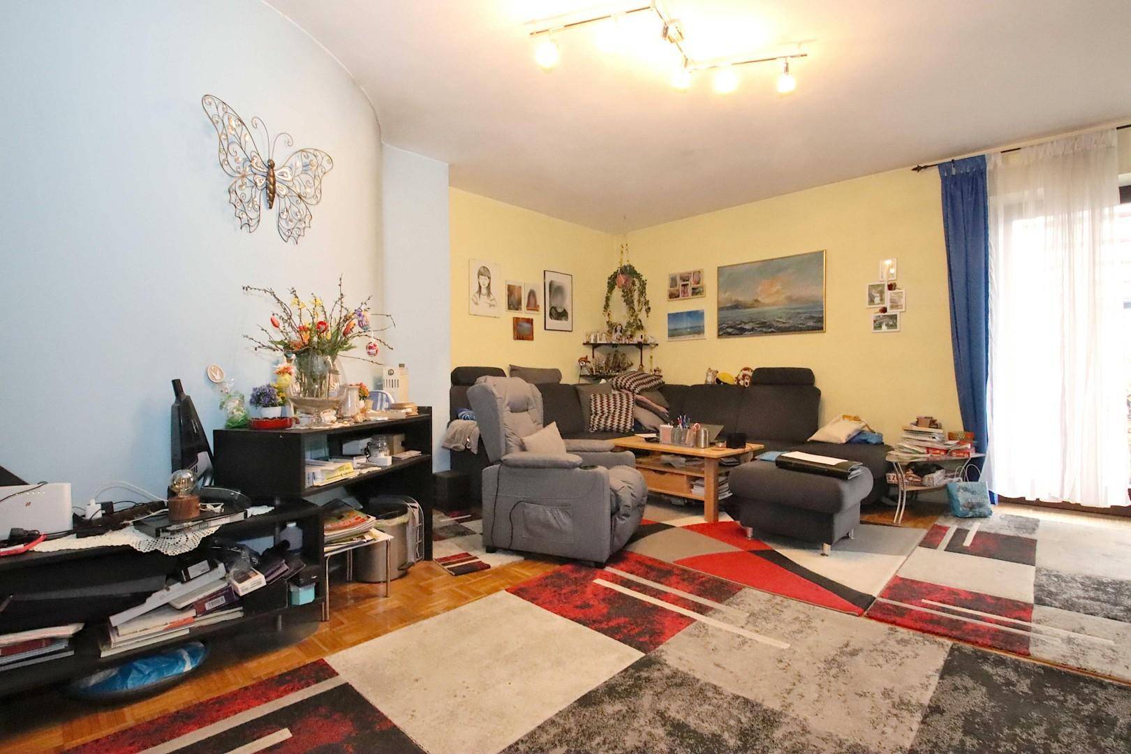 Helles Wohnzimmer mit bequemen Sofas, einem Sessel und farbenfroher Dekoration an den Wänden.