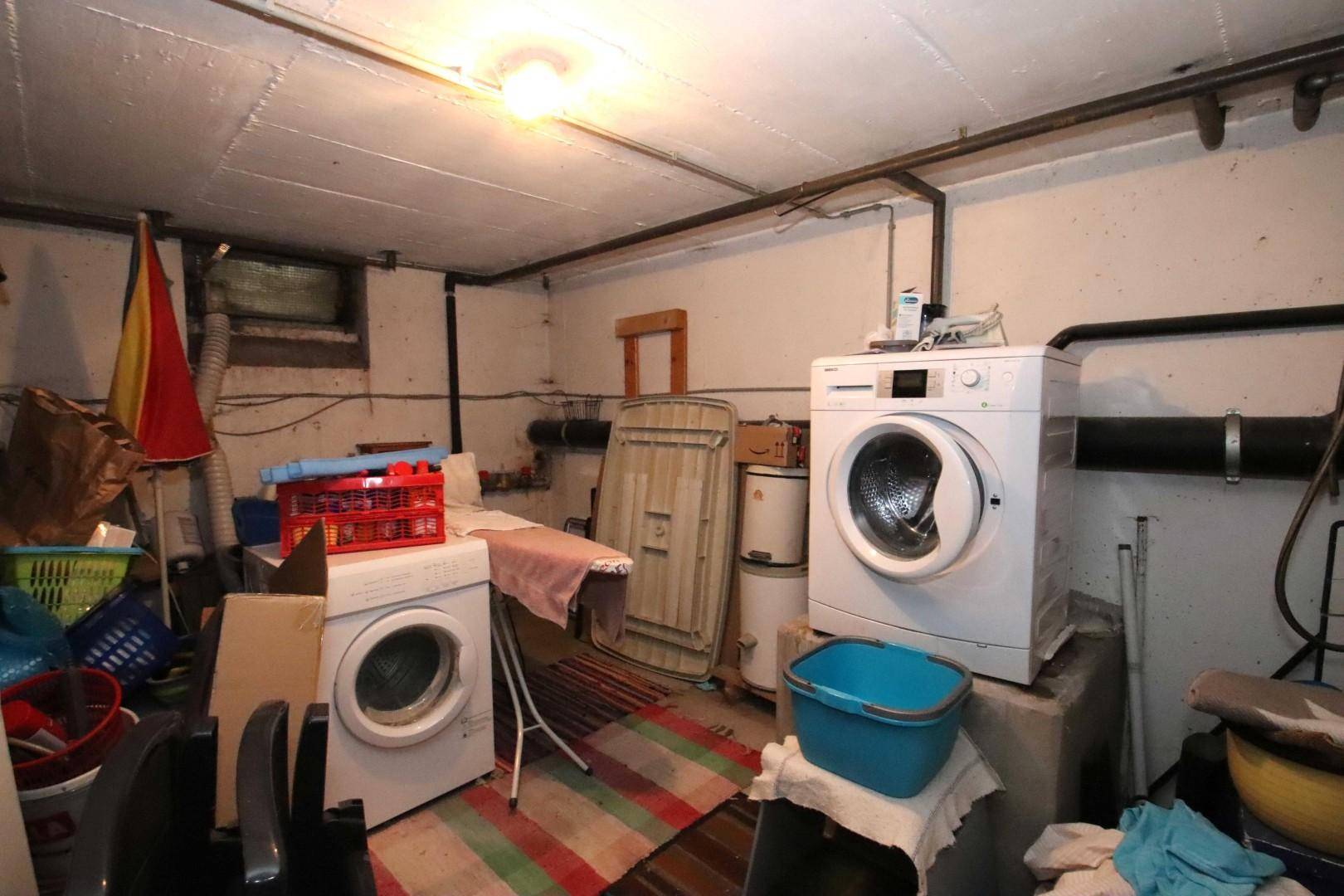 Praktischer Hauswirtschaftsraum im Keller mit zwei Waschmaschinen und Bügelbrett.