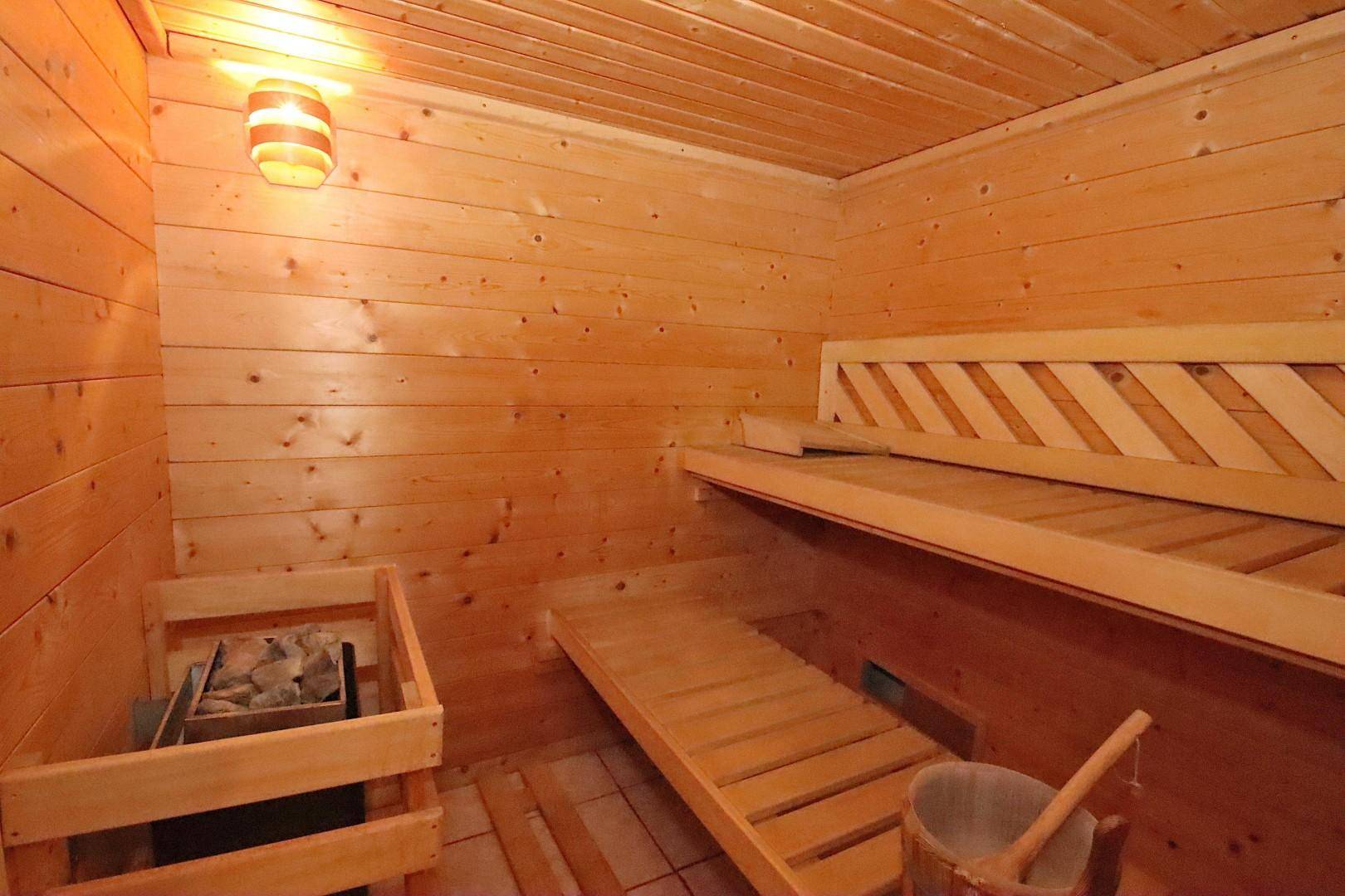 Gemütliche Holzsauna mit Bänken und einem traditionellen Saunaofen für Entspannung.