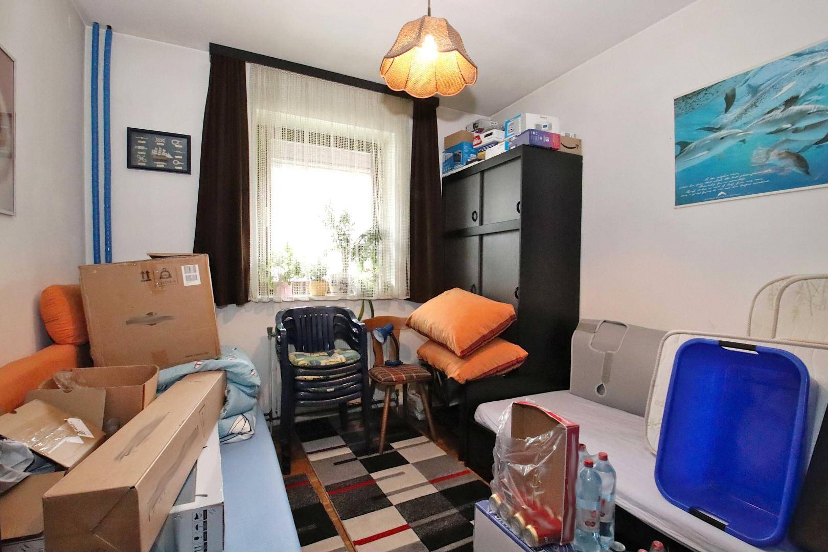 Zimmer mit Einzelbett, Stauraum und einem Fenster, das viel Tageslicht hereinlässt.