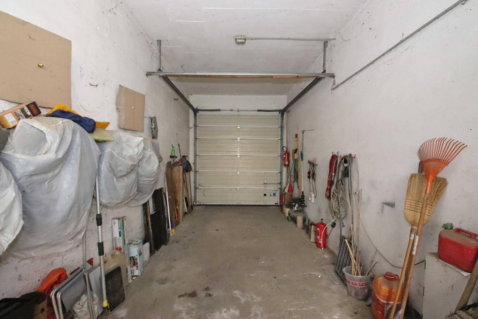 Geräumige Garage mit geschlossenem Tor und Stauraum für Werkzeuge und Gegenstände.
