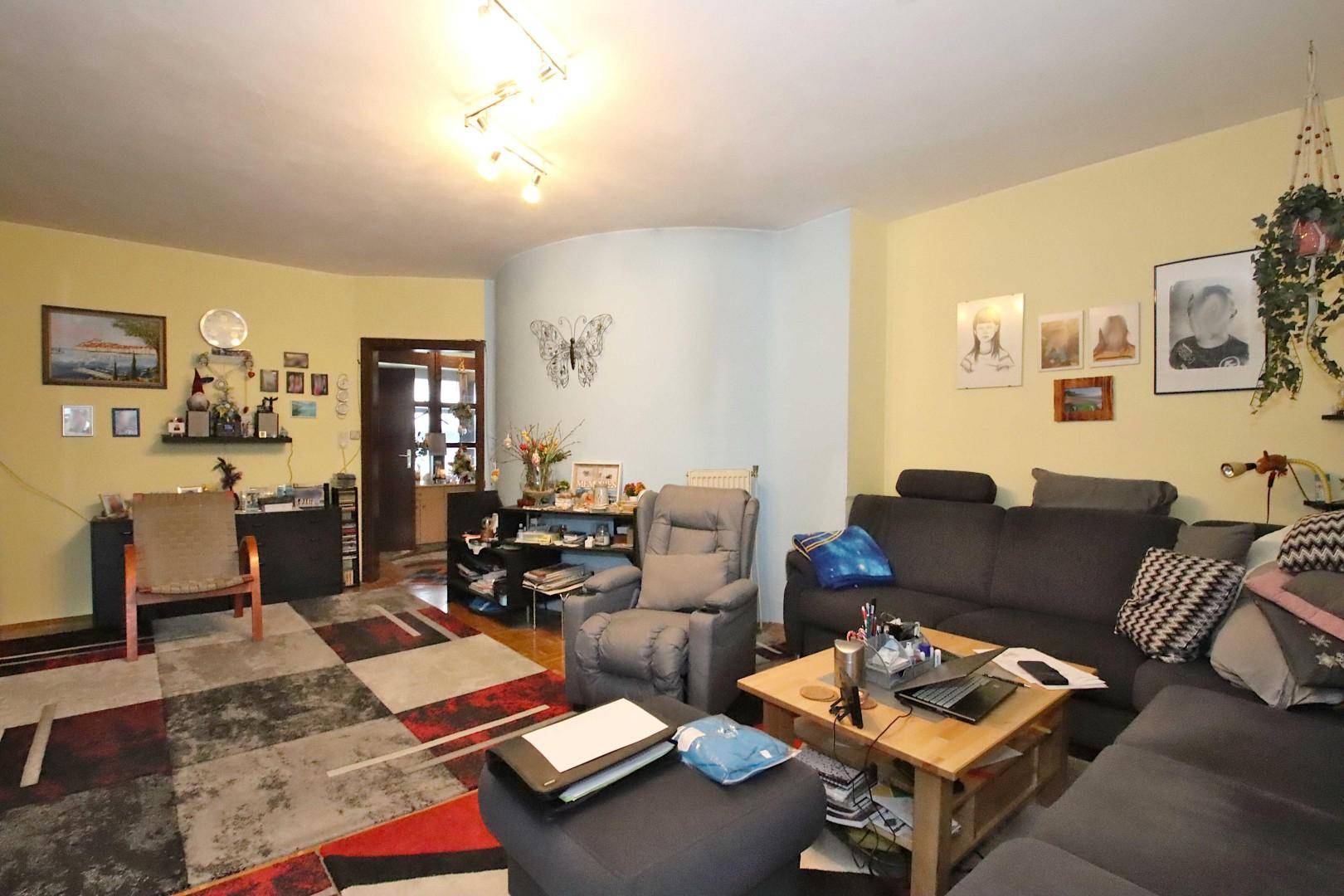 Geräumiges Wohnzimmer mit verschiedenen Sitzbereichen und einem Arbeitsplatz.