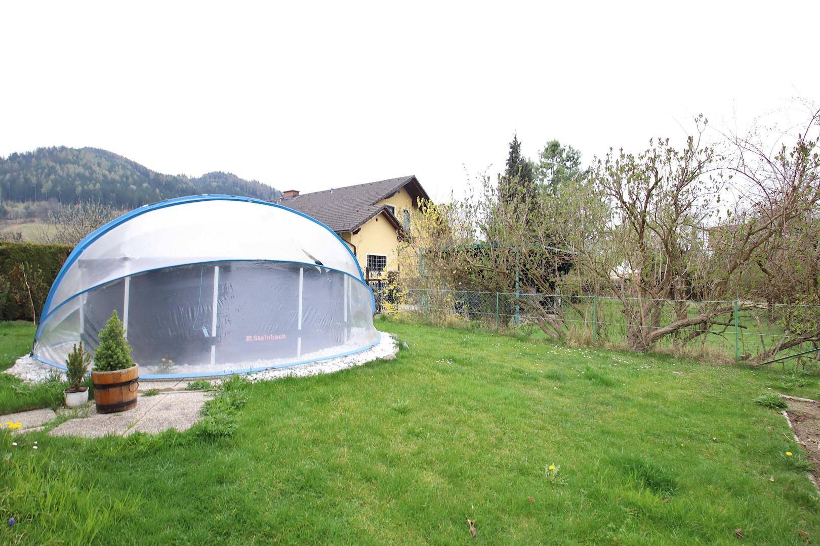 Großer Gartenbereich mit einem überdachten Pool und weitem Blick auf die umliegende Landschaft.
