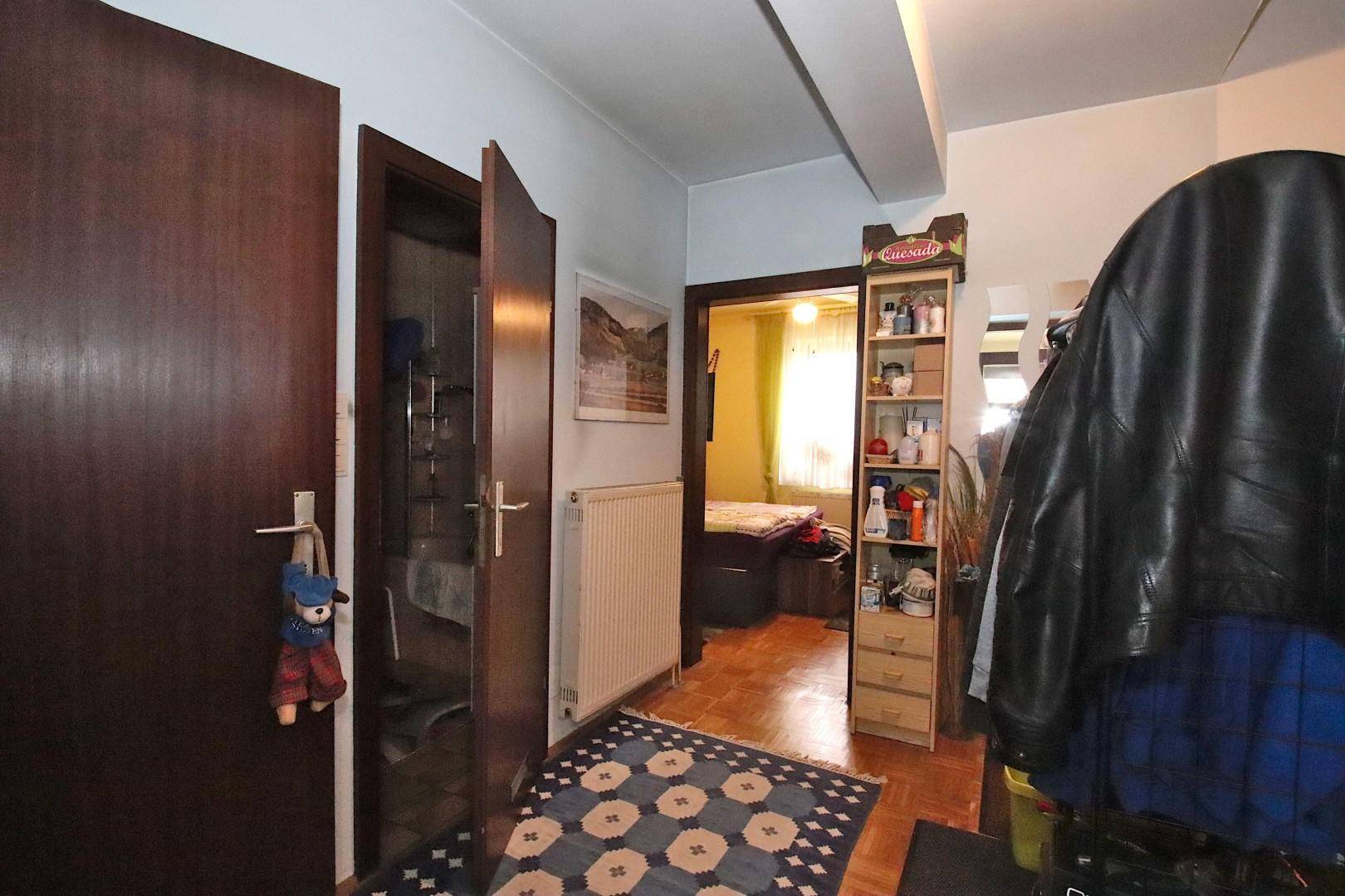 Flur mit Heizkörper, Zugang zu einem Schlafzimmer und praktischen Ablagemöglichkeiten.