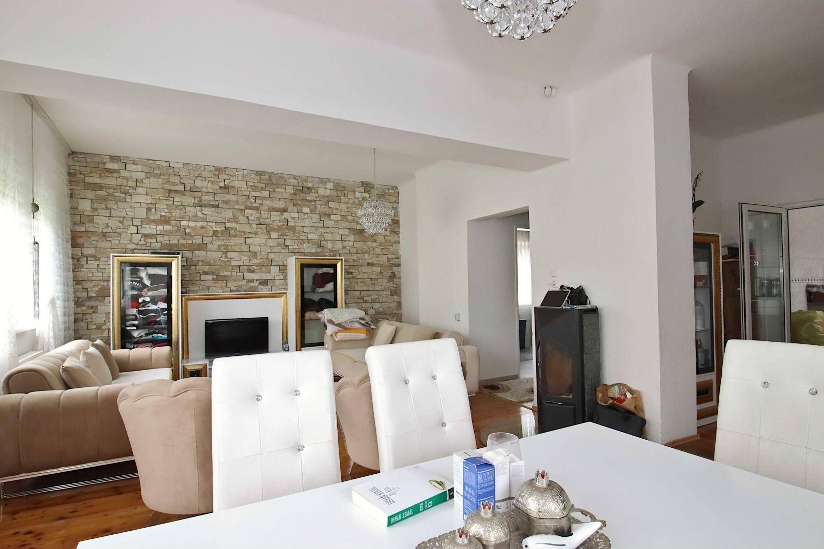Offener Wohn- und Essbereich mit Steinwand, Holzboden und moderner Einrichtung.