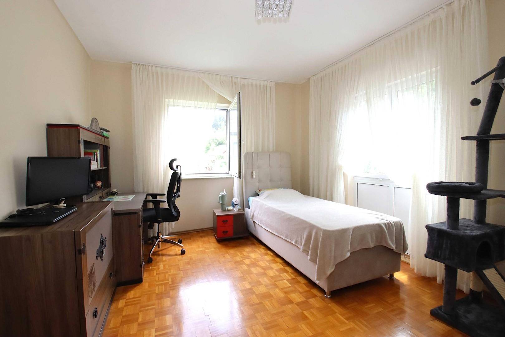 Geräumiges Schlafzimmer mit Holzboden, Schreibtisch und großem Fenster.