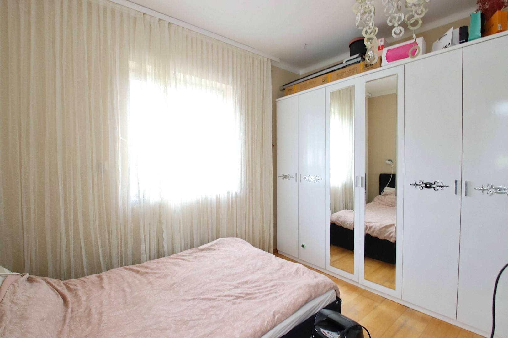Schlafzimmer mit großem Bett, Spiegelschränken und hellem Holzboden.