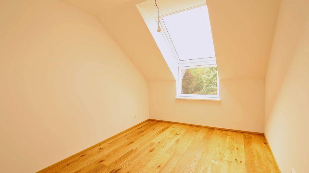 Heller Raum im Dachgeschoss mit Holzboden und großem Dachfenster.