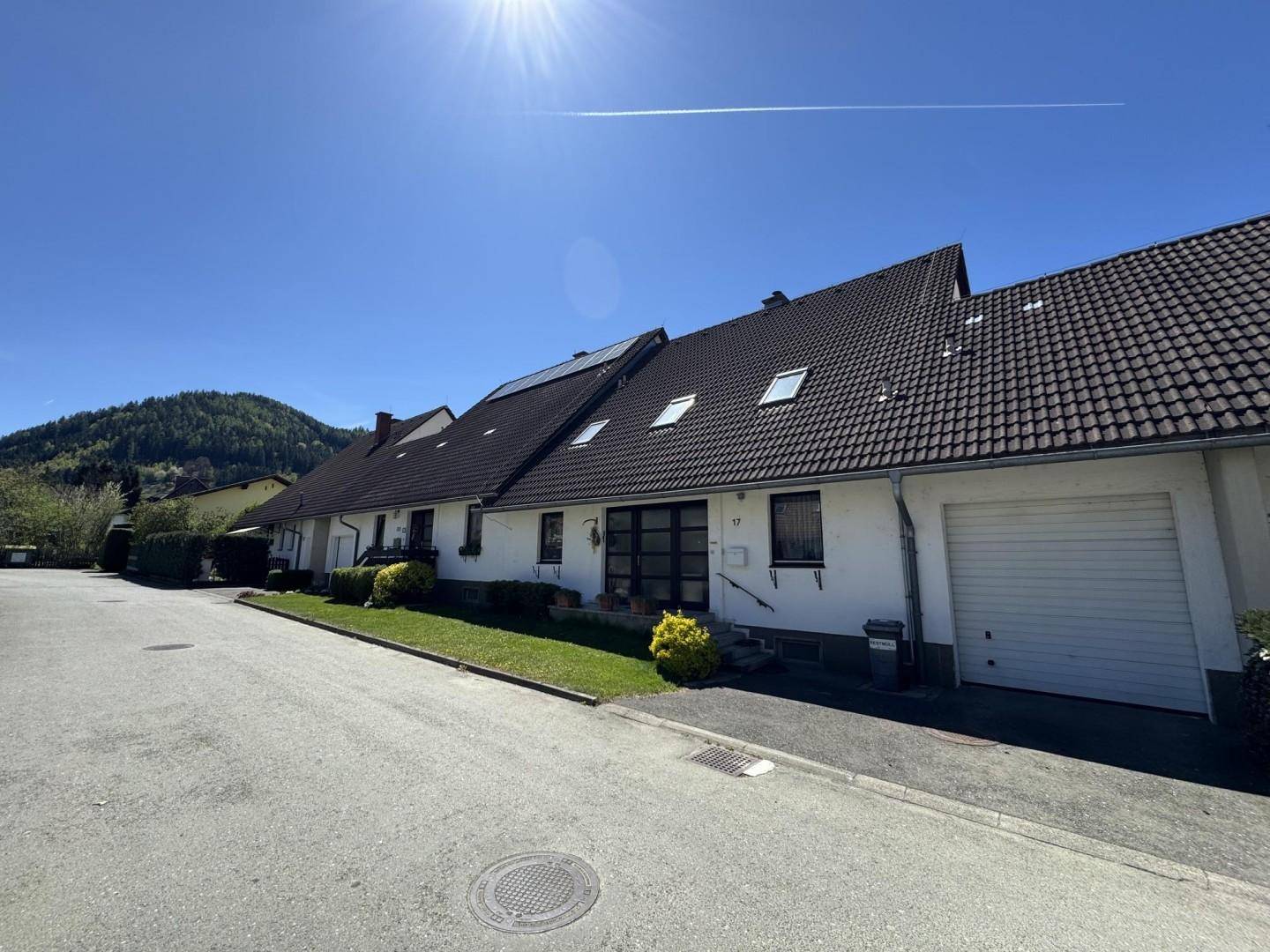 Vorderansicht des Hauses mit Garage, Vorgarten und sonniger Lage an der Straße.