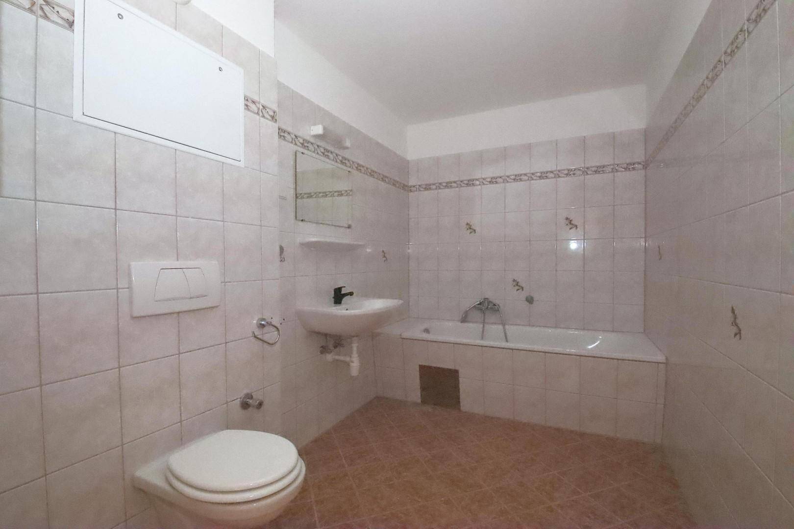 Badezimmer mit hellen Fliesen, Badewanne, WC und Waschbecken in gutem Zustand.