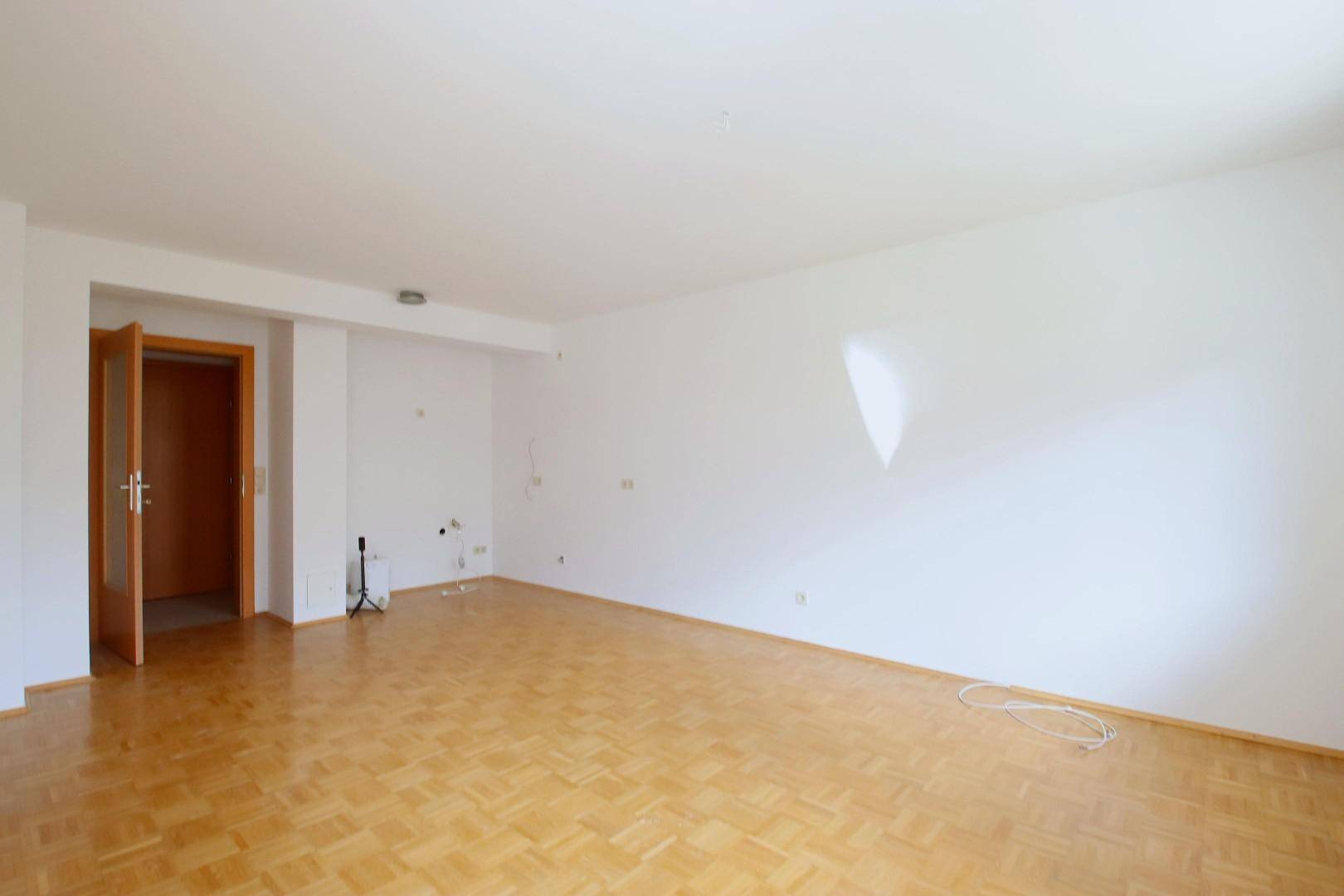 Leerer Raum mit Parkettboden und weiß gestrichenen Wänden, ideal für Wohn- oder Schlafzimmer.