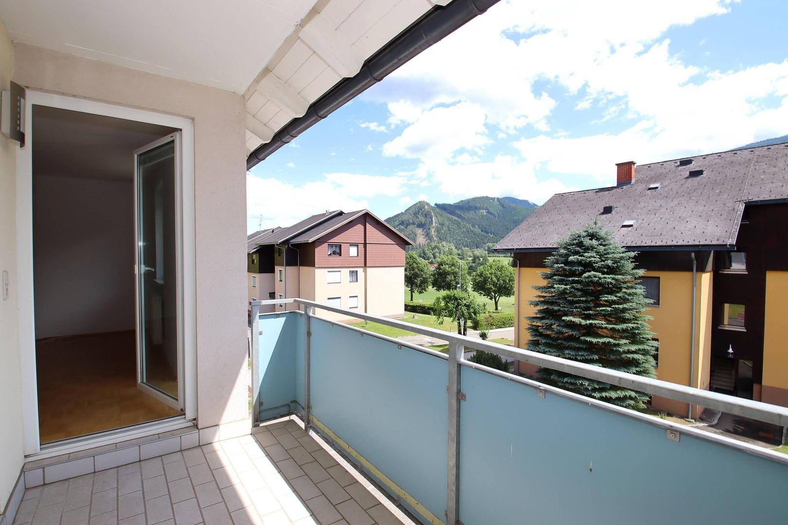 Balkon mit Fliesenboden und Blick auf die umliegenden Häuser und grüne Hügel.
