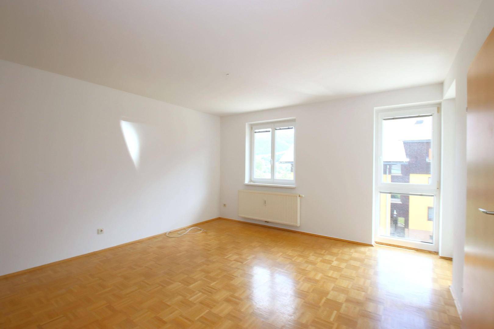Geräumiges, helles Zimmer mit Parkettboden und großen Fenstern, bereit zur individuellen Gestaltung.