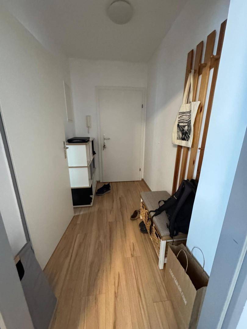Heller Flur mit Holzboden, Garderobe und praktischer Schuhablage.