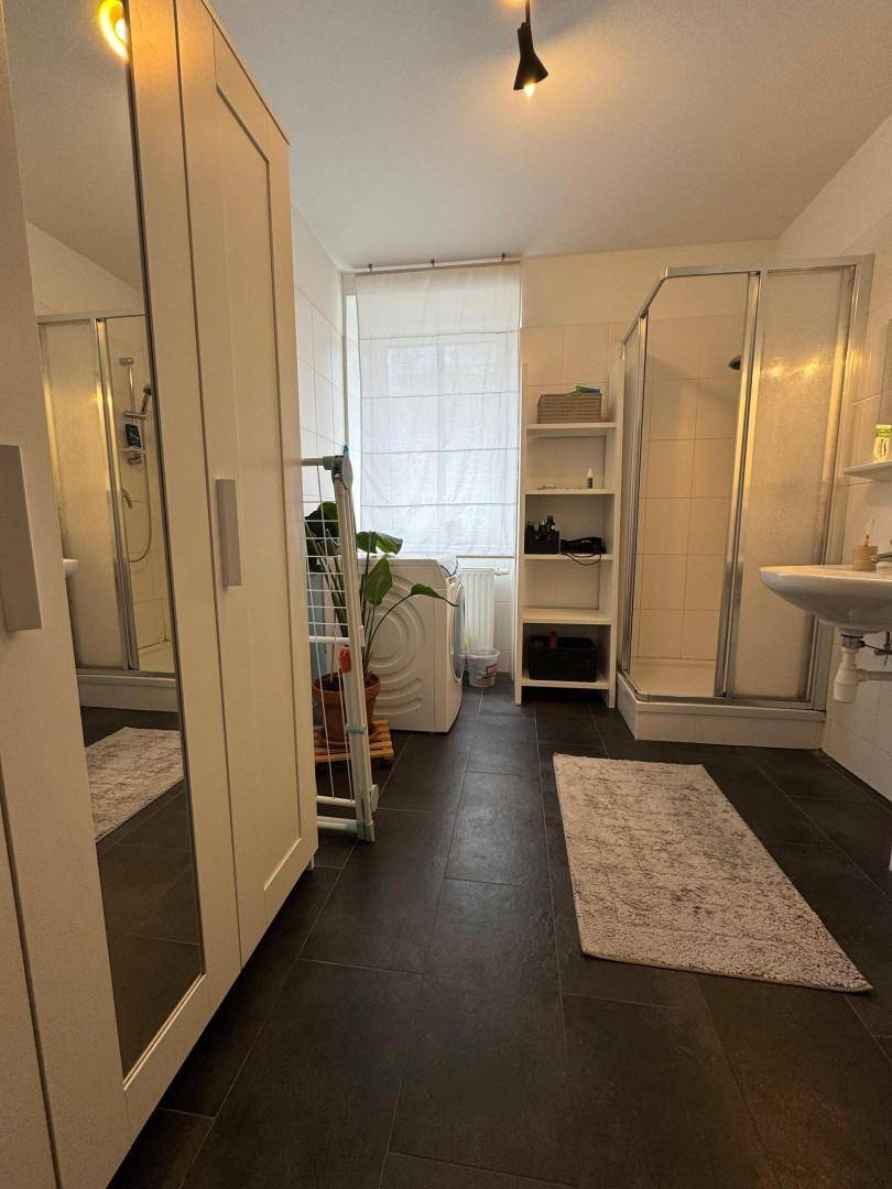 Modernes Badezimmer mit zwei Duschkabinen, Waschbecken und Waschmaschine.