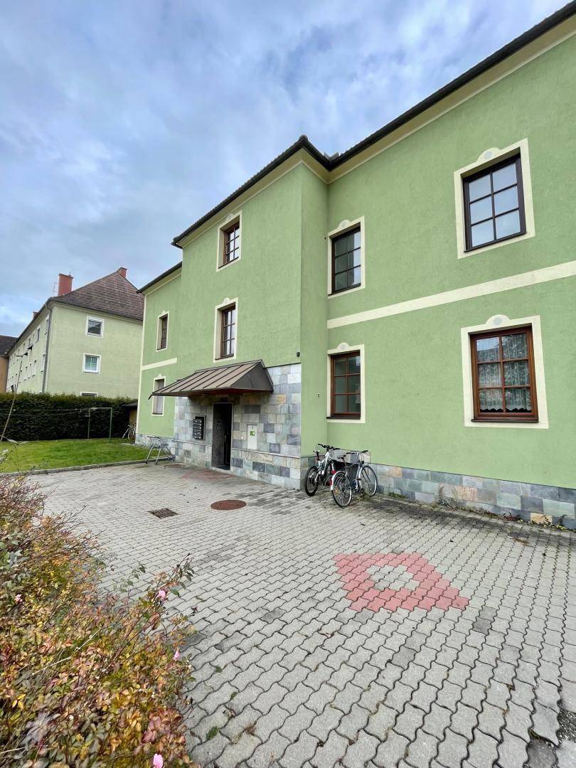 Eingangsbereich des Gebäudes mit hellgrüner Fassade und gepflastertem Vorplatz.