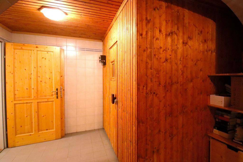 Innenraum mit einer Holzkabine, die eine Sauna beherbergt, und einer Holztür.