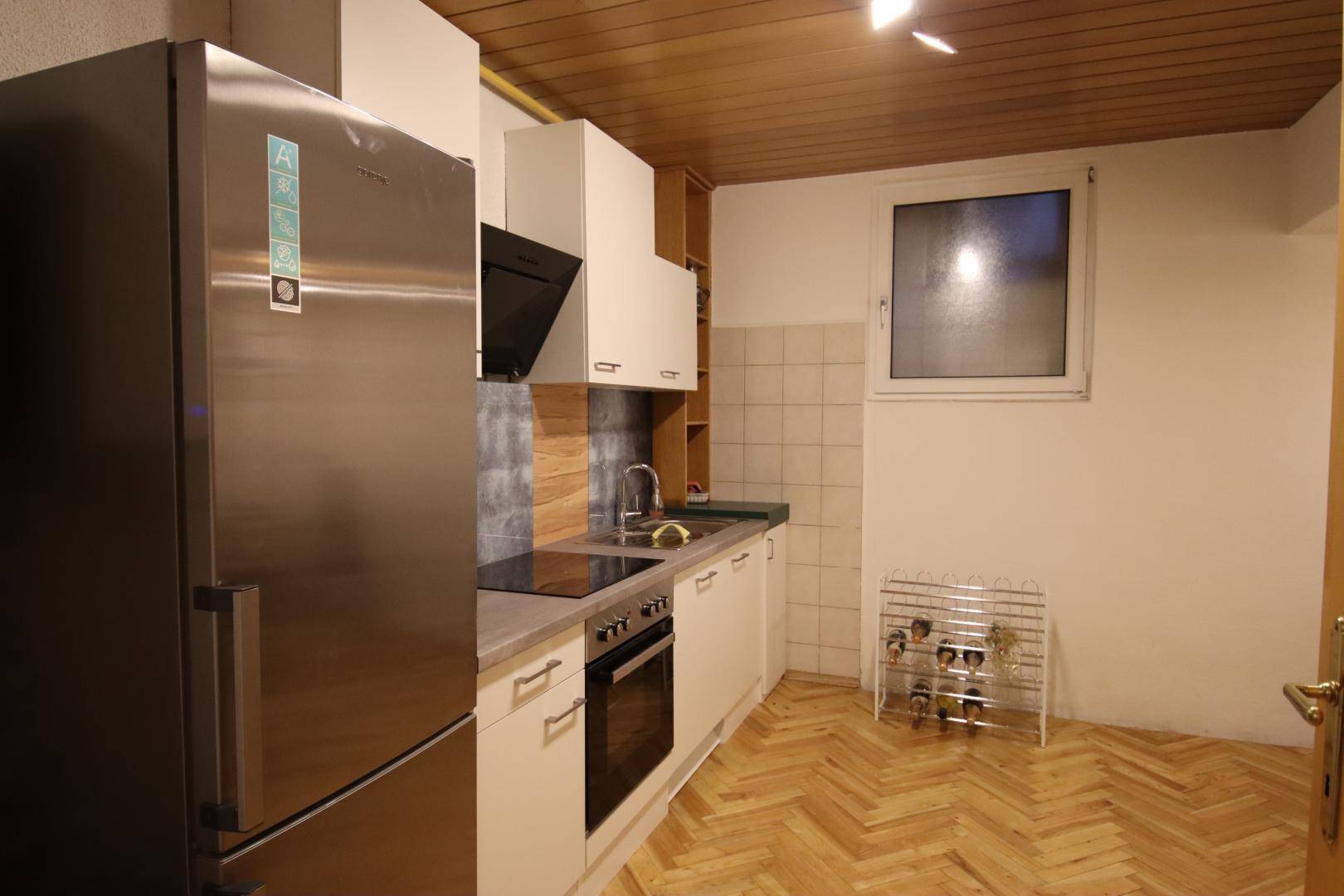Funktionale Küche mit modernen Geräten, Holzdecke und einem Fenster, ausgestattet mit Kühlschrank und Herd.