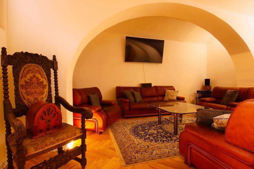 Gemütlicher Wohnbereich im Keller mit Gewölbedecken, Ledersofas und einem Teppich, beleuchtet durch warmes Licht.