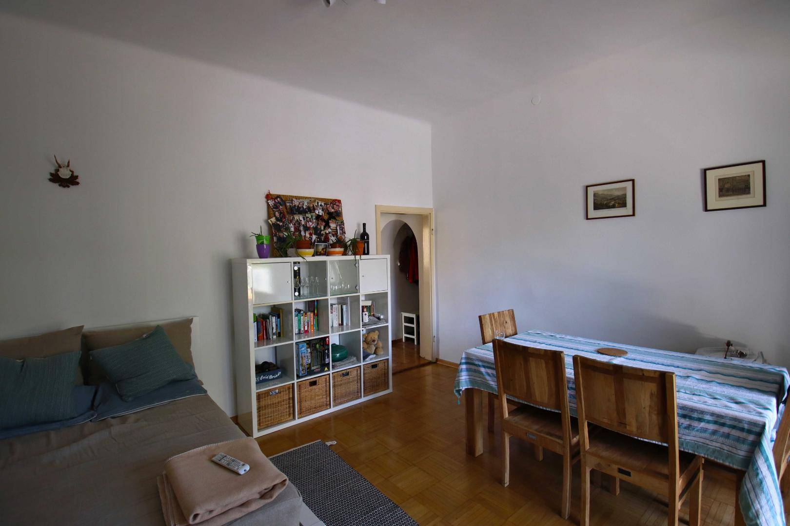 Kombinierter Wohn- und Essbereich mit Holzboden, Bett, Regal und Esstisch.
