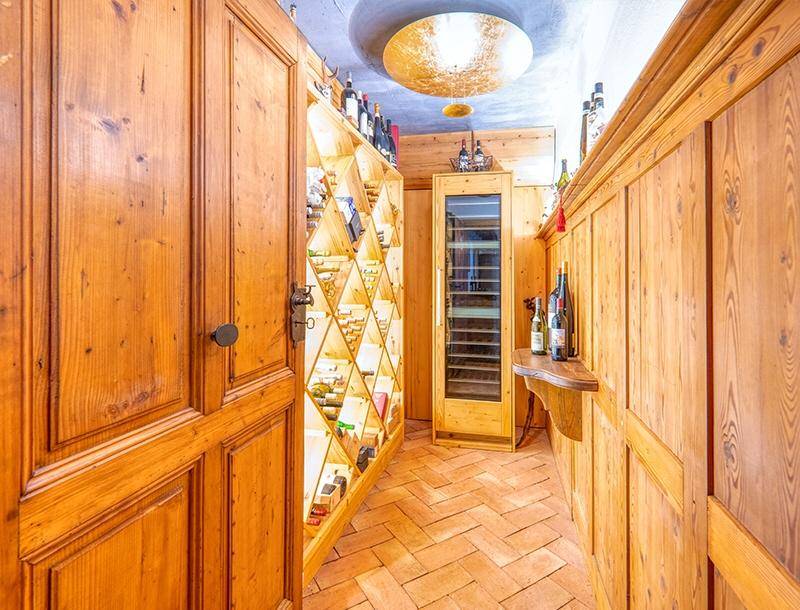 Rustikaler Weinkeller mit Holzregalen, Terrakotta-Boden und integriertem Weinkühlschrank für Sammler.